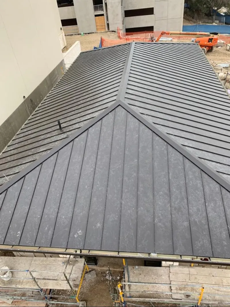 Commercial metal roof construction with crane equipment in Falls